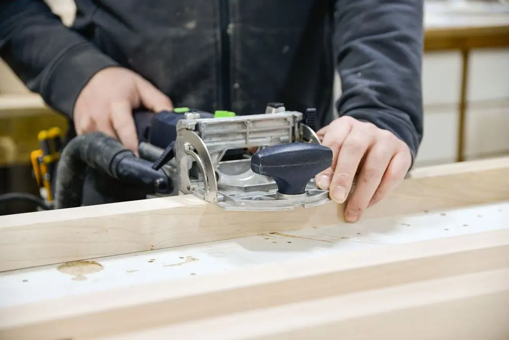 Woodworker using a router tool for custom wood joinery at Homestead Woodworks, showcasing expert craftsmanship and precision